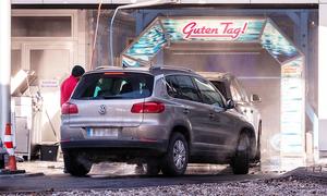 Ein Auto fährt in winterlicher Umgebung in eine Waschanlage ein.