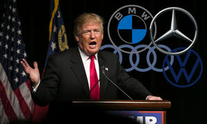 Trump steht an einem Podium und die Logos deutscher Automarken sind im Hintergrund ins Bild eingefügt.