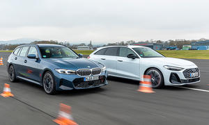 BMW 3er Touring und Audi A5 Avant fahren nebeneinander auf einer Flugzeuglandebahn, von vorne rechts fotografiert.