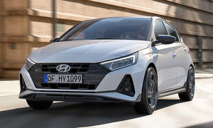 Der Hyundai i20 N Line (2024) fährt in urbaner Umgebung, von vorne links fotografiert.