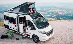 Das Panoramabild zeigt den Adria Twin Sports mit aufgestellem Dach auf einer Klippe von schräg seitlich.