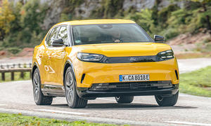 Der Ford Capri (2024) bei der Fahrt über eine kurvige Landstraße; von schräg vorne fotografiert.