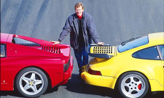 Walter Röhrl steht zwischen Ferrari 512 TR/Porsche 911 Turbo
