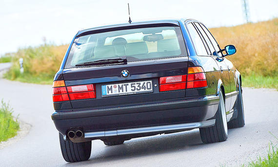 Der BMW M5 Touring (E34) fahrend von schräg hinten fotografiert.