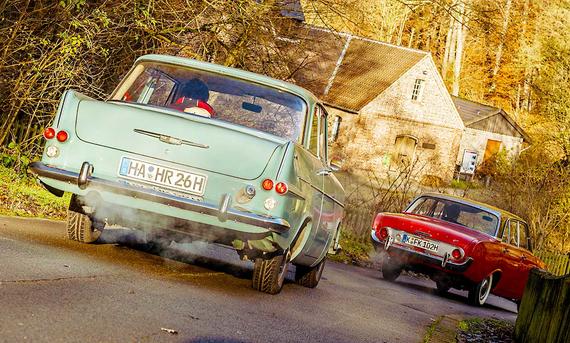 Der Opel Rekord P2 und der Ford Taunus 17M P3 fahrend von hinten fotografiert.