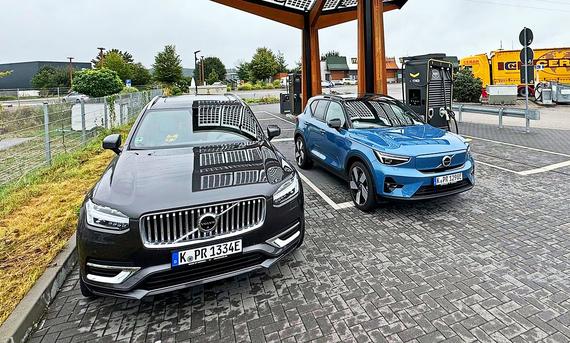 Der Volvo XC90 &amp; Volvo XC40 Rechargestehen an einer Tankstelle nahe einer Autobahn.