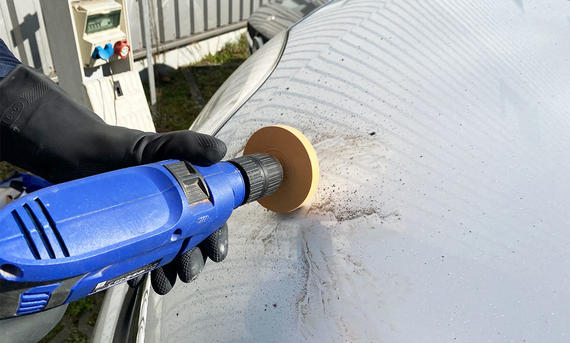 Ein Folienradierer auf einer Bohrmaschine im Einsatz an einem Auto.