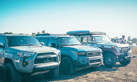 Drei Generationen des Toyota Land Cruiser statisch von schräg vorne fotografiert.