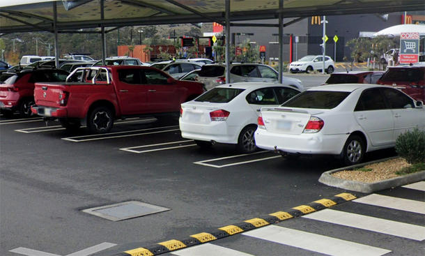 Heckansicht geparkter Autos auf dem Parkplatz eines australischen Einkaufszentrums mit Rechtecken als Parkplatzmarkierungen, schräg