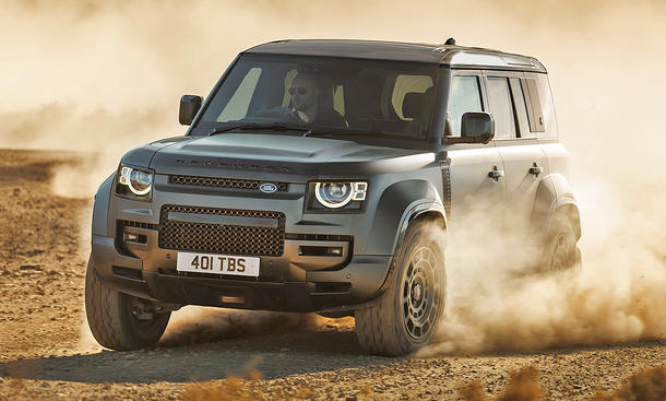 Land Rover Defender Octa (2024) fährt im Gelände und wirbelt Staub auf. Ansicht des Fahrzeugs von vorne links.