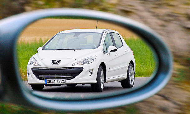 Der Peugeot 308 GTi fahrend von vorne im Rückspiegel fotografiert.