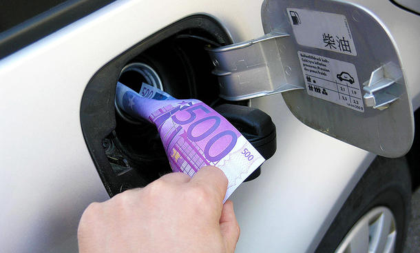 Spritkosten senken: Symbolbild zeigt Geldschein im Tankeinfüllstutzen eines Autos.