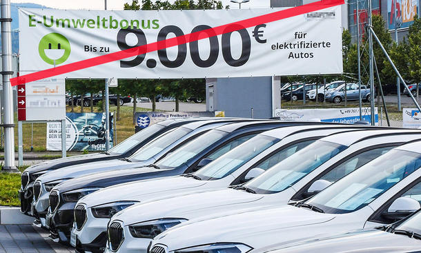 Autohändler mit durchgestrichenem Plakat zur E-Auto-Prämie