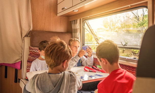 Vier Kinder spielen ein Kartenspiel in einem Wohnmobil