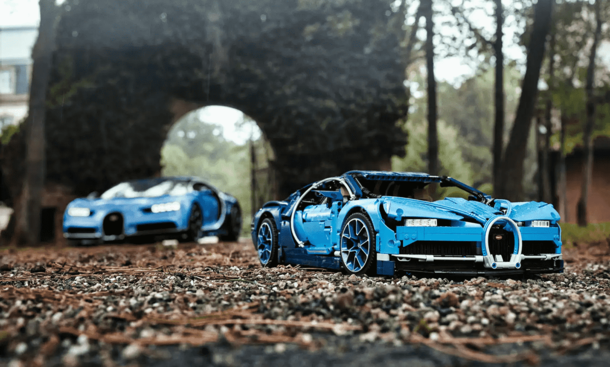 Der Lego Technic Bugatti Chiron steht im Laub vor dem Original.