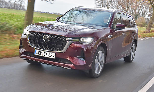 Mazda CX-80 fährt auf einer Landstraße, Ansicht von vorne links.