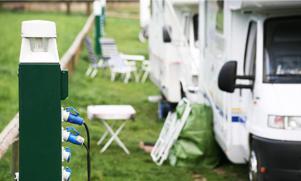 Ein Wohnmobil am Stromanschluss auf einem Campingplatz.