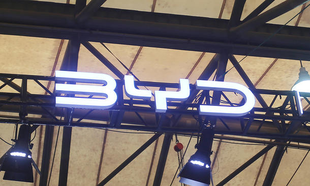 BYD-Logo hängt unter einem Messedach.