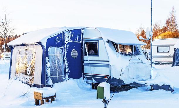 Camper richtig dämmen: Symbolbild zeigt eingeschneiten Wohnwagen auf einem Campingplatz