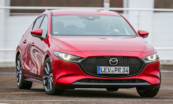 Der Mazda3 (2019) fährt auf einer Straße, von vorne rechts fotografiert.