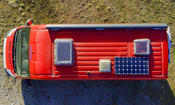 Das Bild zeigt eine Drohnenaufnahme von einem Campervan. Das Fahrzeug mit Solarpanel auf dem Dach ist aus der Vogelperspektive zu sehen.