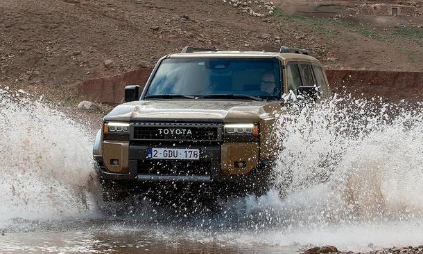 Der Toyota Land Cruiser (2024) fährt durch Wasser; von vorne fotografiert.